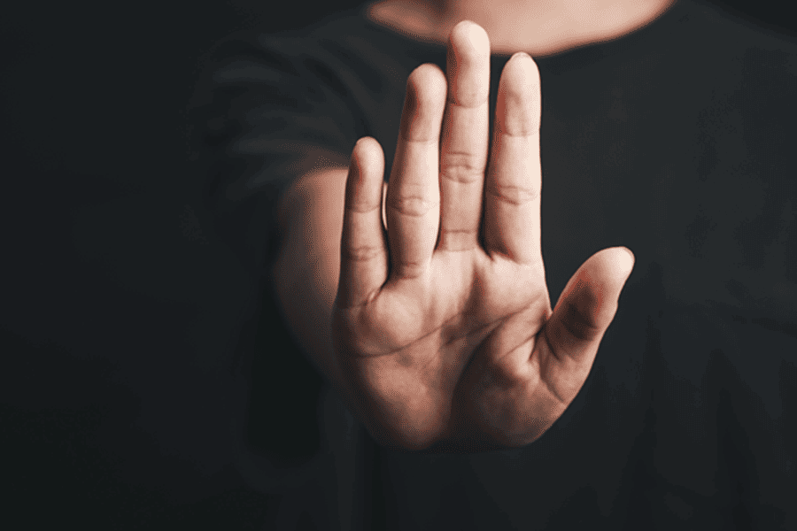 Person raising an open hand in a stop gesture on a dark background – Bet Blocker features benefits and how to self-exclude from gambling